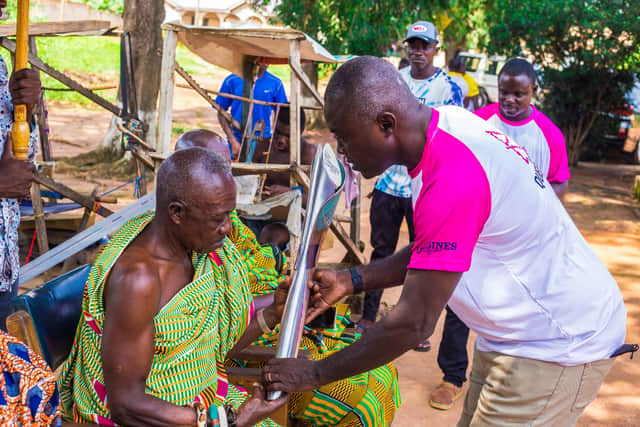 A Birmingham 2022 Batonbearer handing the Baton to a local man in Ghana