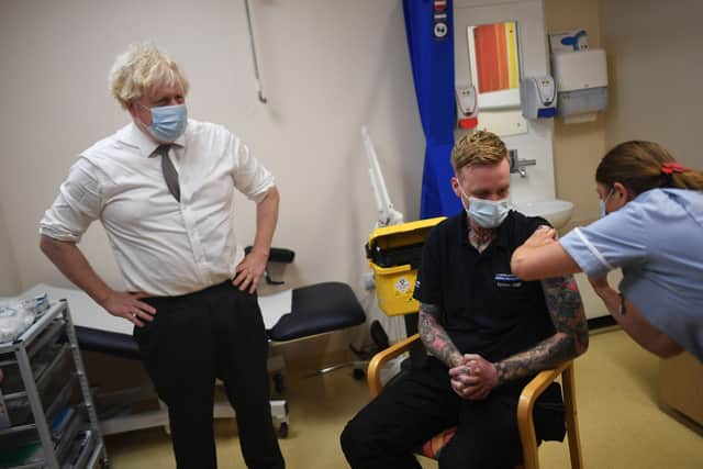 Boris Johnson looks on as a patient received their Covid-19 booster shot during a visit to Hexham General Hospital. (Credit: Getty)