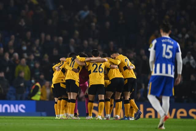 Wolves players form a team huddle on the pitch ahead of the English Premier League football match between Brighton and Hove Albion and Wolverhampton Wanderers at the American Express Community Stadium