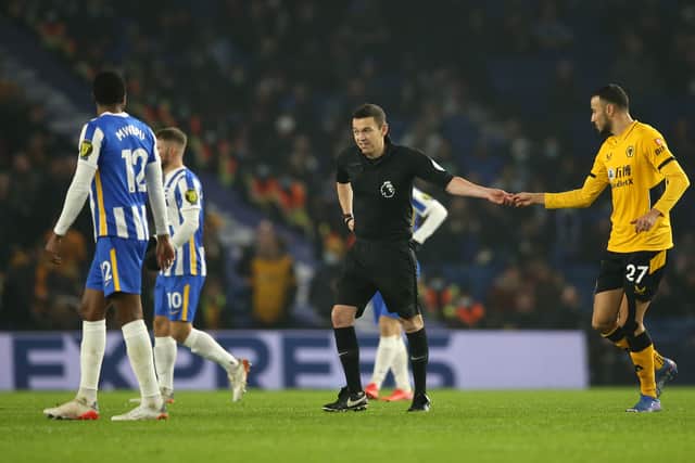 Match Referee Tony Harrington interacts with Romain Saiss of Wolverhampton Wanderers during the Premier League match between Brighton & Hove Albion and Wolverhampton Wanderers 