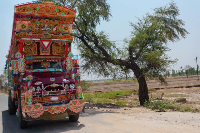 <p>Lahore, Pakistan: A Jingle Truck drives an a small rural road in the countryside</p>