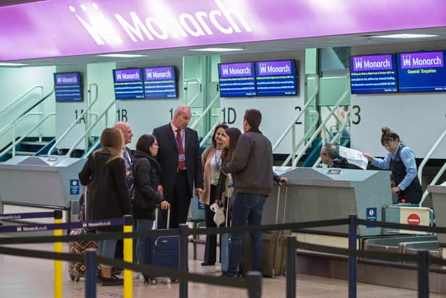 Airport staff talk with passengers at the check-in area for Monarch Airlines, in the departures lounge of Birmingham Airport in Birmingham (OLI SCARFF/GETTY)