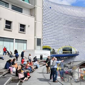 People sit outside the Bullring shopping centre in Birmingham. (Photo by JUSTIN TALLIS/AFP via Getty Images)