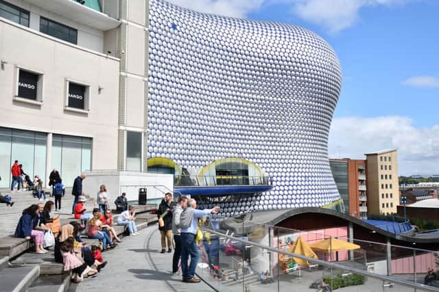 People sit outside the Bullring shopping centre in Birmingham. (Photo by JUSTIN TALLIS/AFP via Getty Images)