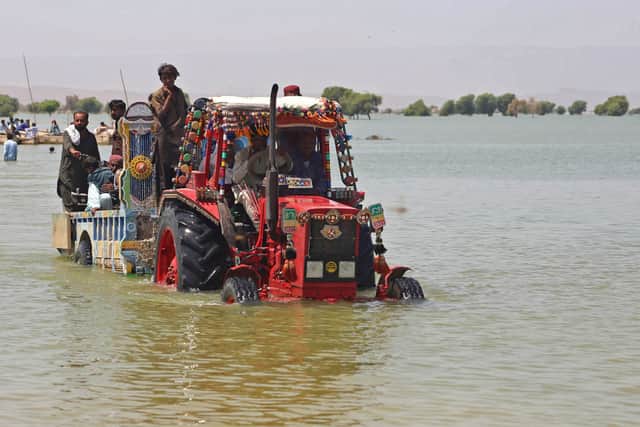  Displaced people who fled from flood-hit areas sit on a tractor to cross a flooded area at Sehwan in Sindh province on August 31, 2022 (Photo by Akram SHAHID / AFP) (Photo by AKRAM SHAHID/AFP via Getty Images)