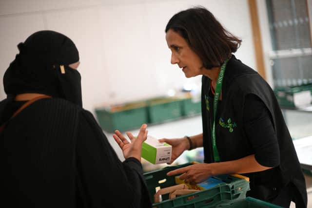 A member of staff (R) speaks with a member of the public inside a foodbank (Photo by DANIEL LEAL/AFP via Getty Images)