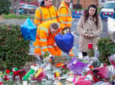 Floral tributes and members of the public paying their respects at Babbs Mill Lake, Kingshurst, Solihull