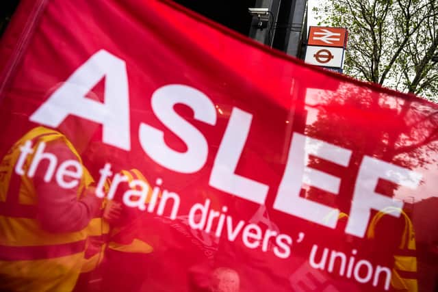 A group of rail workers are seen through a ASLEF union flag. Credit: Leon Neal/Getty Images.