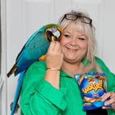 Karen Godwin with Mango the parrot who was coaxed down from a tree with a packet of Wotsits (Photo - Anita Maric / SWNS)