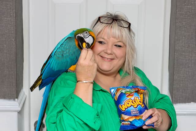 Karen Godwin with Mango the parrot who was coaxed down from a tree with a packet of Wotsits (Photo - Anita Maric / SWNS)