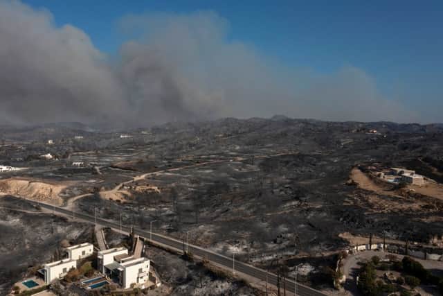 An aerial view shows smoke billowing in background of Kiotari village, on the island of Rhodes on July 24, 2023. Tens of thousands of people have already fled blazes on the island of Rhodes, with many frightened tourists scrambling to get home. Greece has been sweltering under a lengthy spell of extreme heat that has exacerbated wildfire risk and left visitors stranded in peak tourist season. (Photo by SPYROS BAKALIS/AFP via Getty Images)