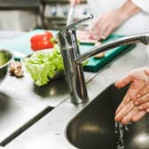 cropped view of female chef washing hands over sink in restaurant kitchen