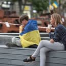 A boy wrapped in Ukrainian national flag sits on a bench next to destroyed Russian military vehicles on August 23, 2023 in Kyiv, Ukraine.