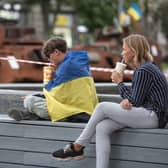 A boy wrapped in Ukrainian national flag sits on a bench next to destroyed Russian military vehicles on August 23, 2023 in Kyiv, Ukraine.