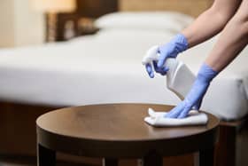 Housemaid wiping bedside table in a hotel room