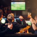 Three men watches football on TV in a sport bar (stock image)
