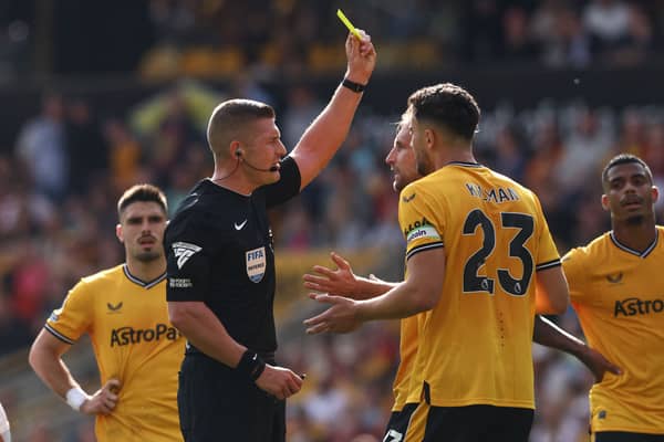 English referee Robert Jones shows a yellow card to Wolverhampton Wanderers' English defender #15 Craig Dawson. (Image: AFP via Getty Images)