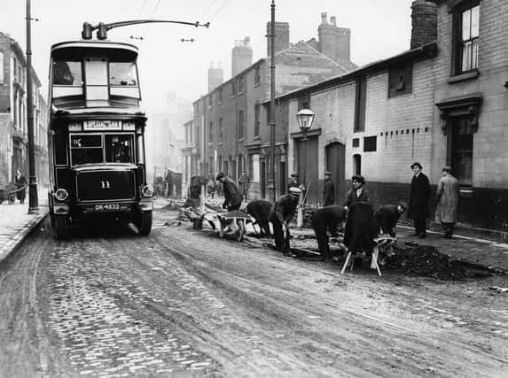 circa 1923:  A 'trackless tram' trolley bus in Birmingham, passing workmen pulling up the old track line.  (Photo by Topical Press Agency/Getty Images