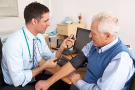Doctor taking senior man's blood pressure