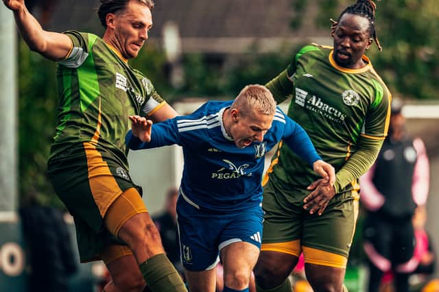 Lye Town's Luke Postle squeezes between two Wulfs players.