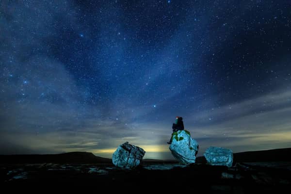 A walker looks up into the night sky above Twistleton Scar in The Yorkshire Dales National Park
