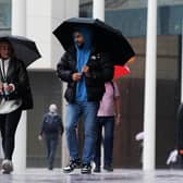 People walk by Centenary Square in Birmingham during a rainy morning