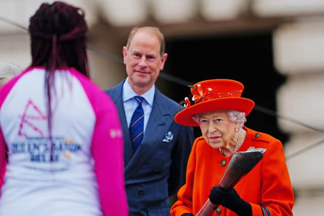 Queen Elizabeth starts the relay by passing her baton to British parasport athlete Kadeena Cox, as Prince Edward looks on